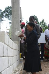 Fylkesdamen legger stein på siste muren og åpner internatet. Den stolte byggmesteren ser på i bakgrunnen